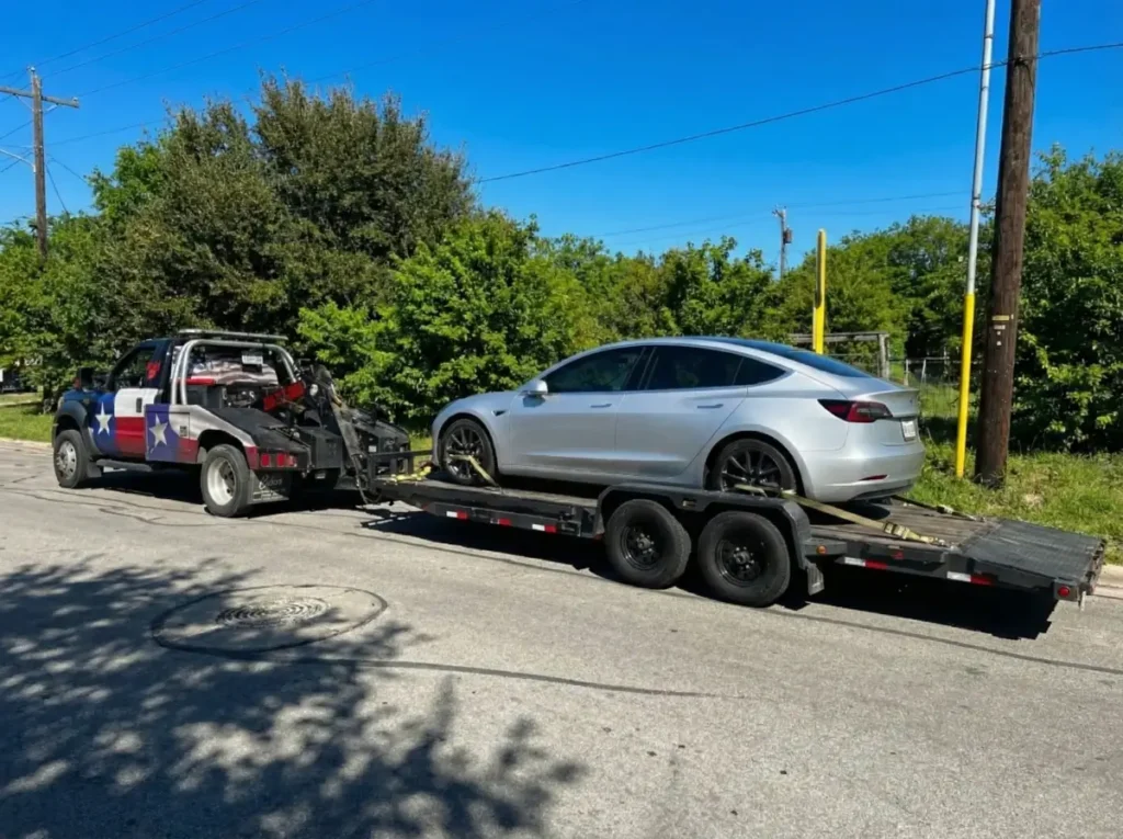 image of a Tesla (EV Vehicle) being towed on a black truck of Texas patriot towing