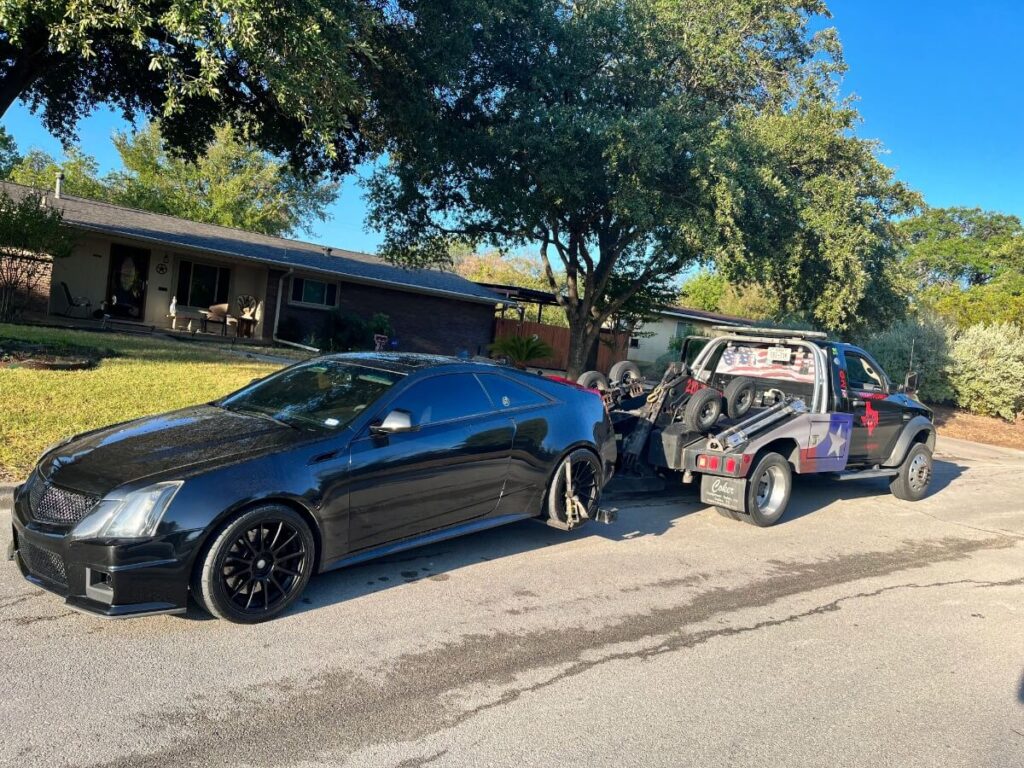 image of a light duty towing job with the tow truck of texas patriot towing pulling a black sedan